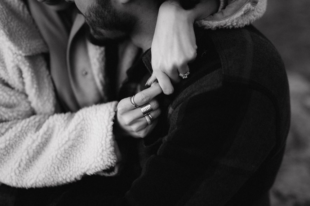 Close up of hands exchanging rings in intimate black and white moment.