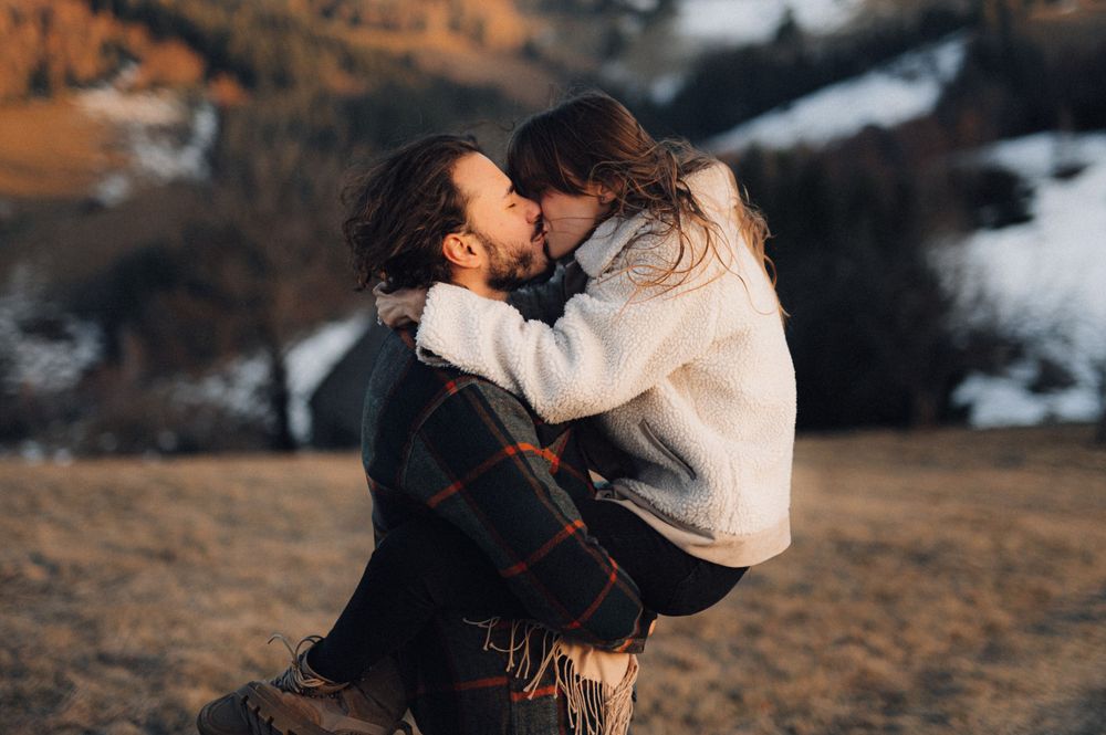 An intimate moment shared between a couple on a mountainside at dusk.