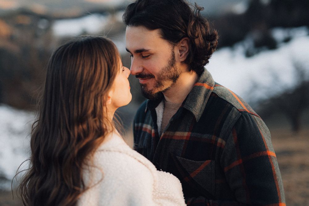 An intimate moment shared between a couple with mountains glowing in warm evening light.
