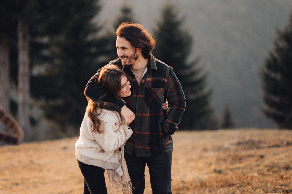 A loving couple shares a tender moment on a mountainside during golden hour in autumn.