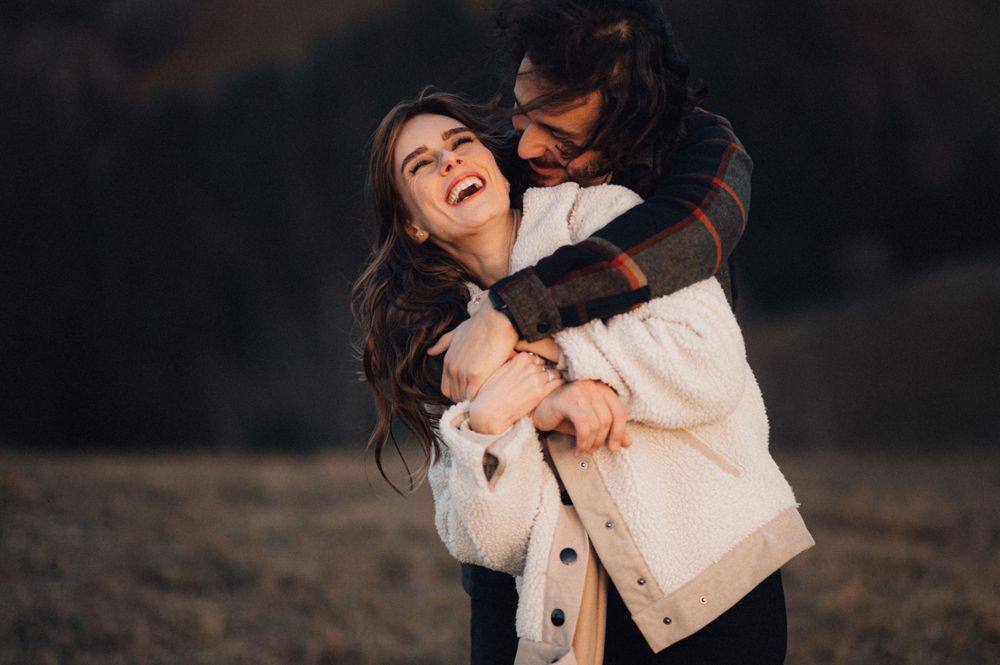 Joyful couple embracing and laughing together in casual winter attire.