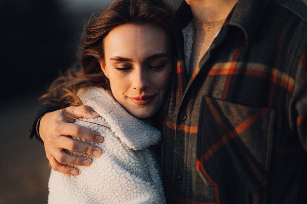 An intimate moment between a couple wearing cozy sweaters during golden hour outdoors.