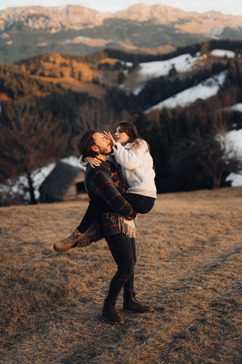 A playful lift against a backdrop of snow-capped mountains during golden hour.