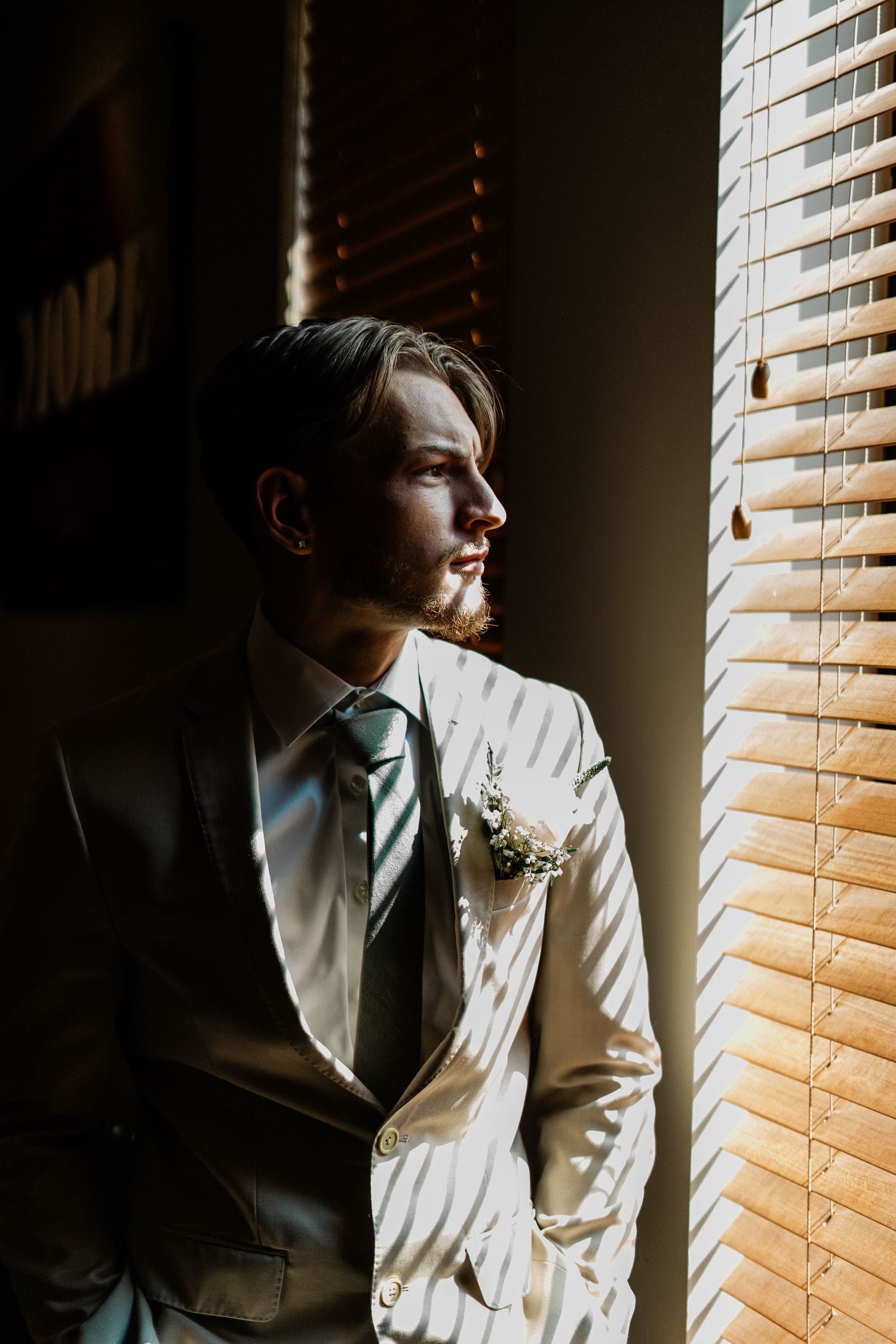 Groom getting ready photos, looking out the window, editorial style