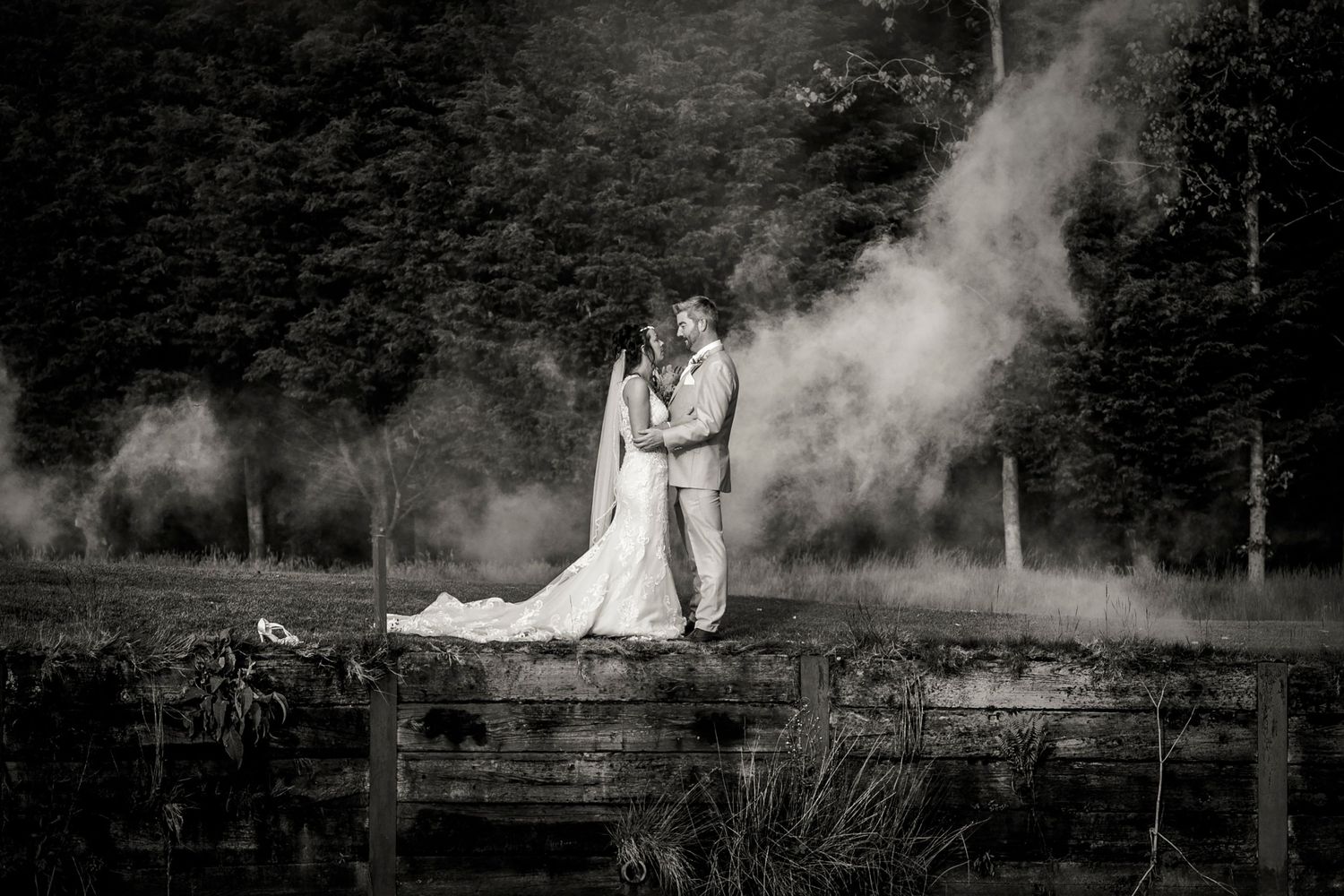 Dramatic black and white wedding photos with atmospheric smoke effects outdoors.