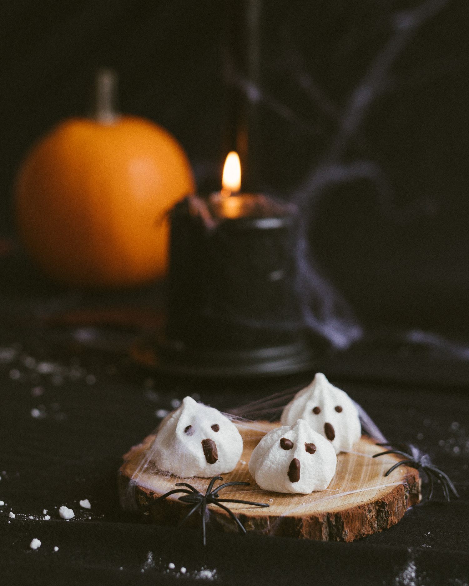 Spøkelsesmarengs for Halloween med svart lys, gresskar og spindelvev i bakgrunnen.