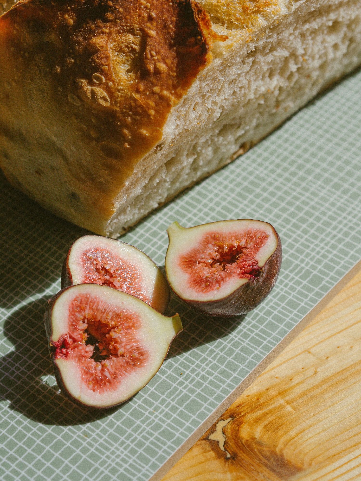 Oppskåret surdeigsbrød og ferske fiken på skjærebrett,