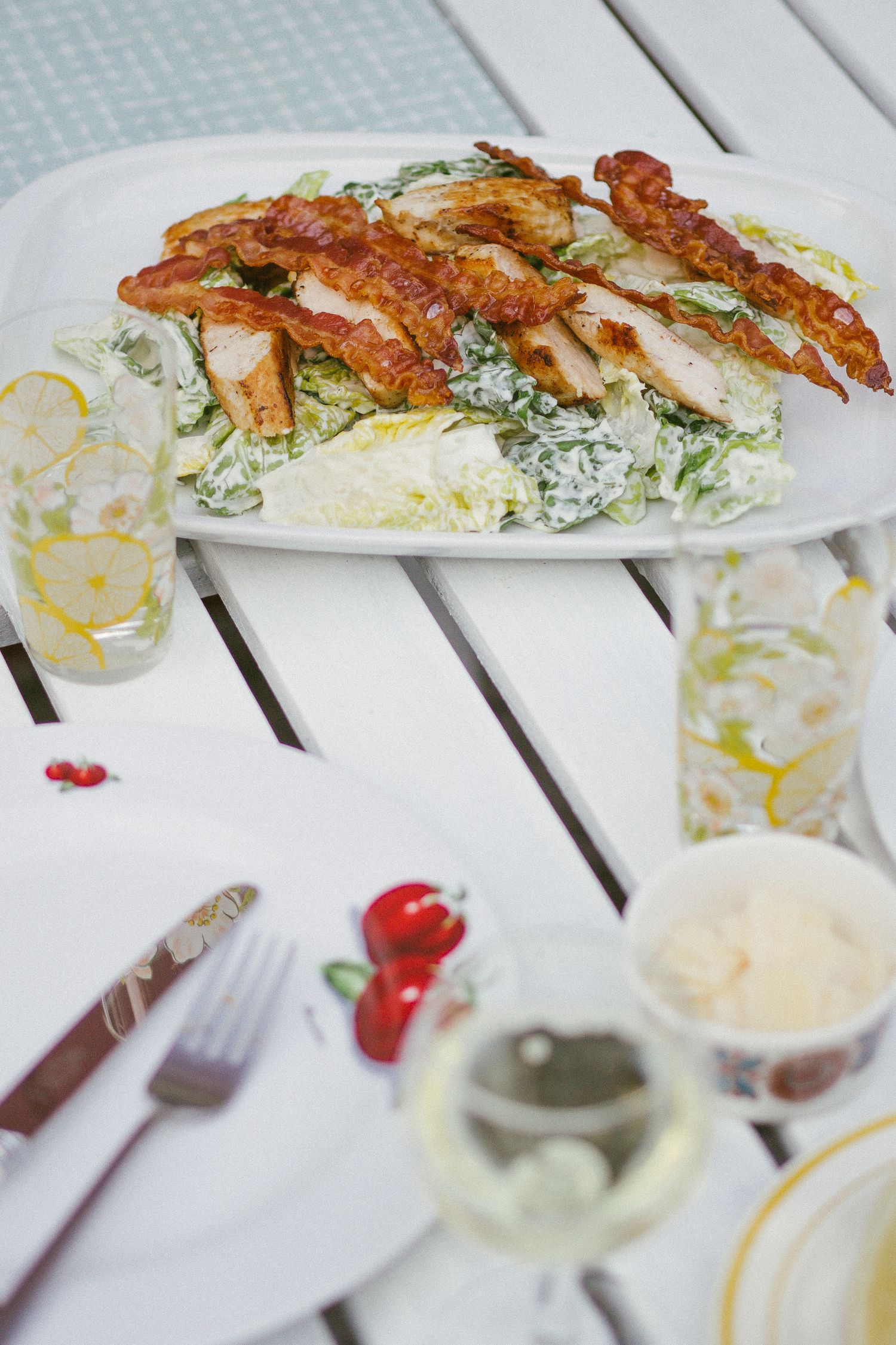 Summery diningtable with white wine and caesar salad.