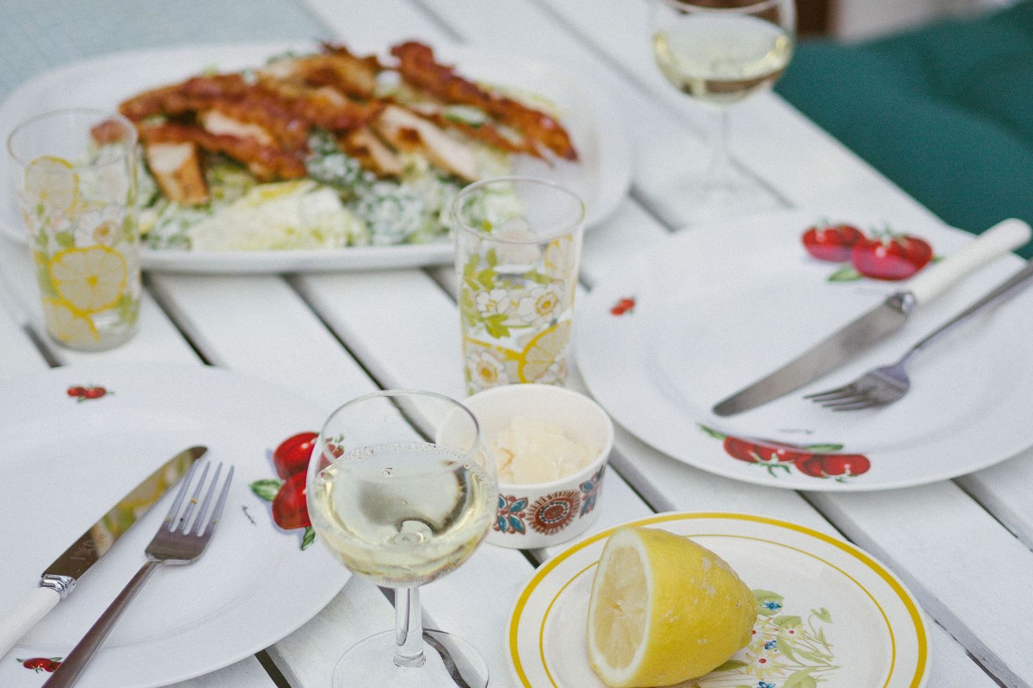 Summery diningtable with white wine and caesar salad.