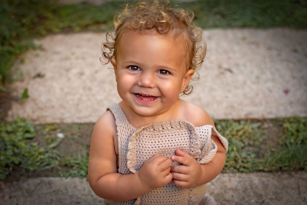 a toddler laughing to the camera in the beautiful Jerusalem Estates garden in Jerusalem, Israel.