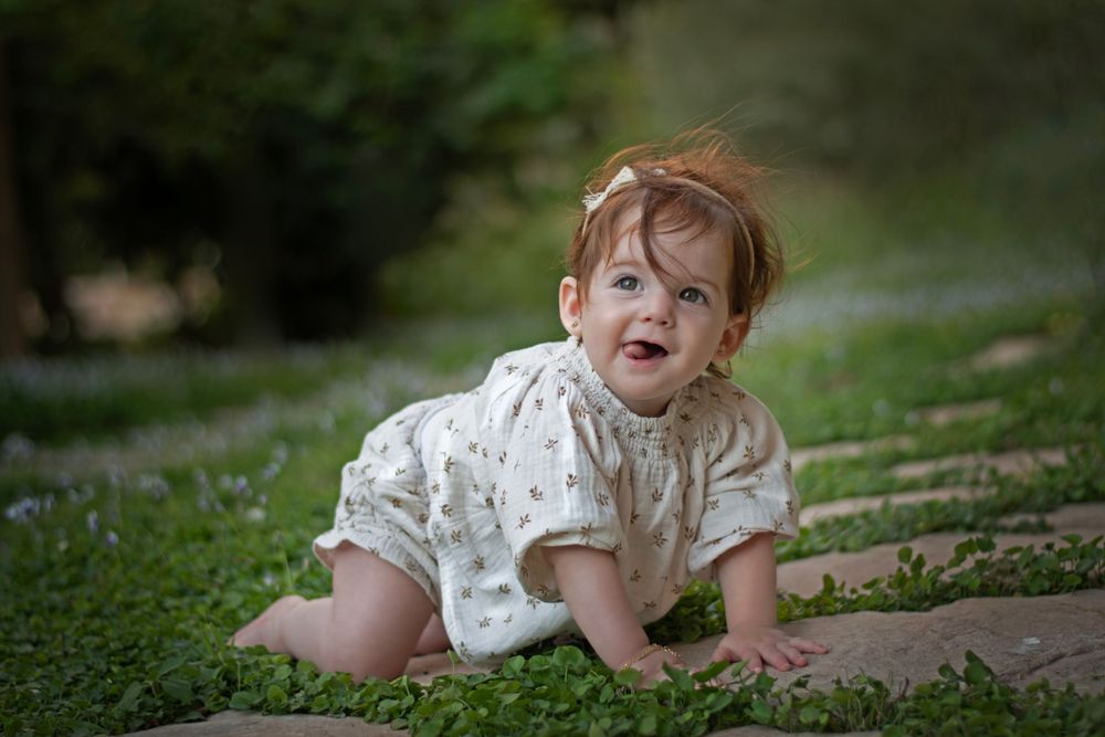 A baby girl happily posing in the magical Jerusalem Estates Garden, Jerusalem.