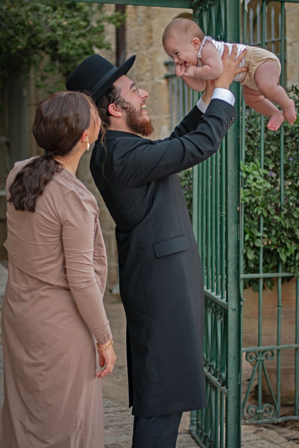 A couple holding their child in the air and smiling to him in Yemin Moshe, Jerusalem, Israel.
