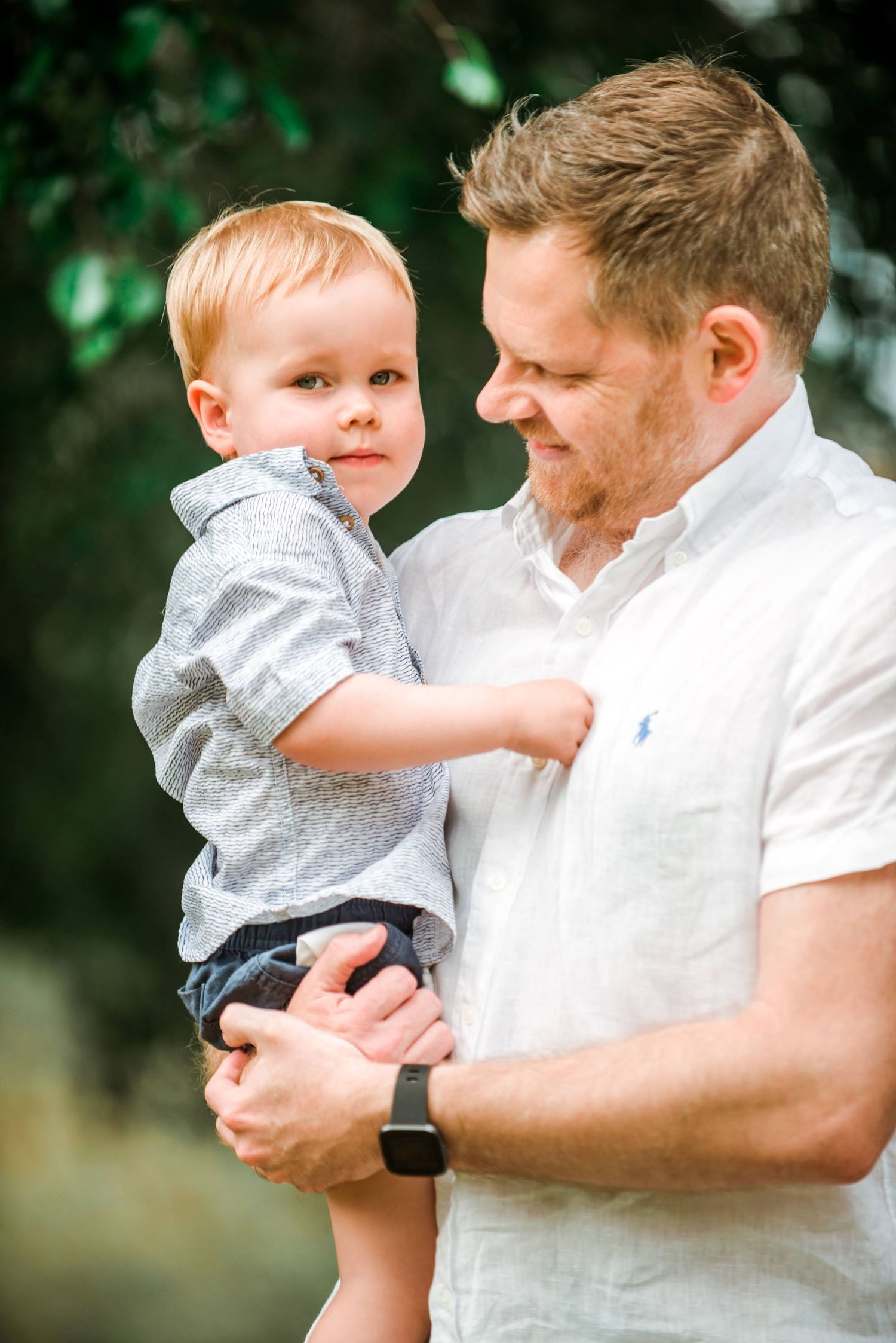 Parent and toddler sharing sweet moment against green natural background.