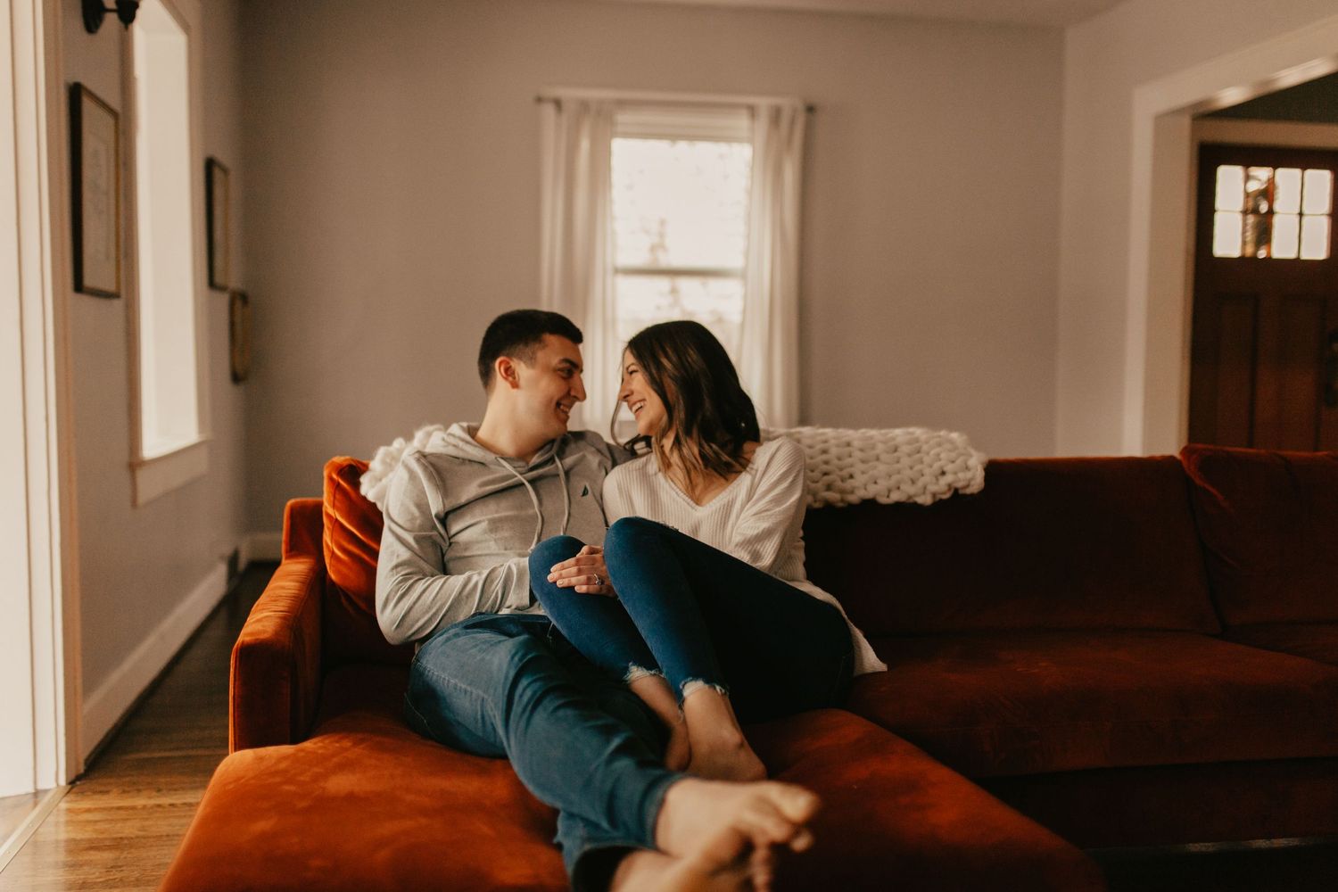 Couple shares an intimate moment on a couch in a warmly lit living room.