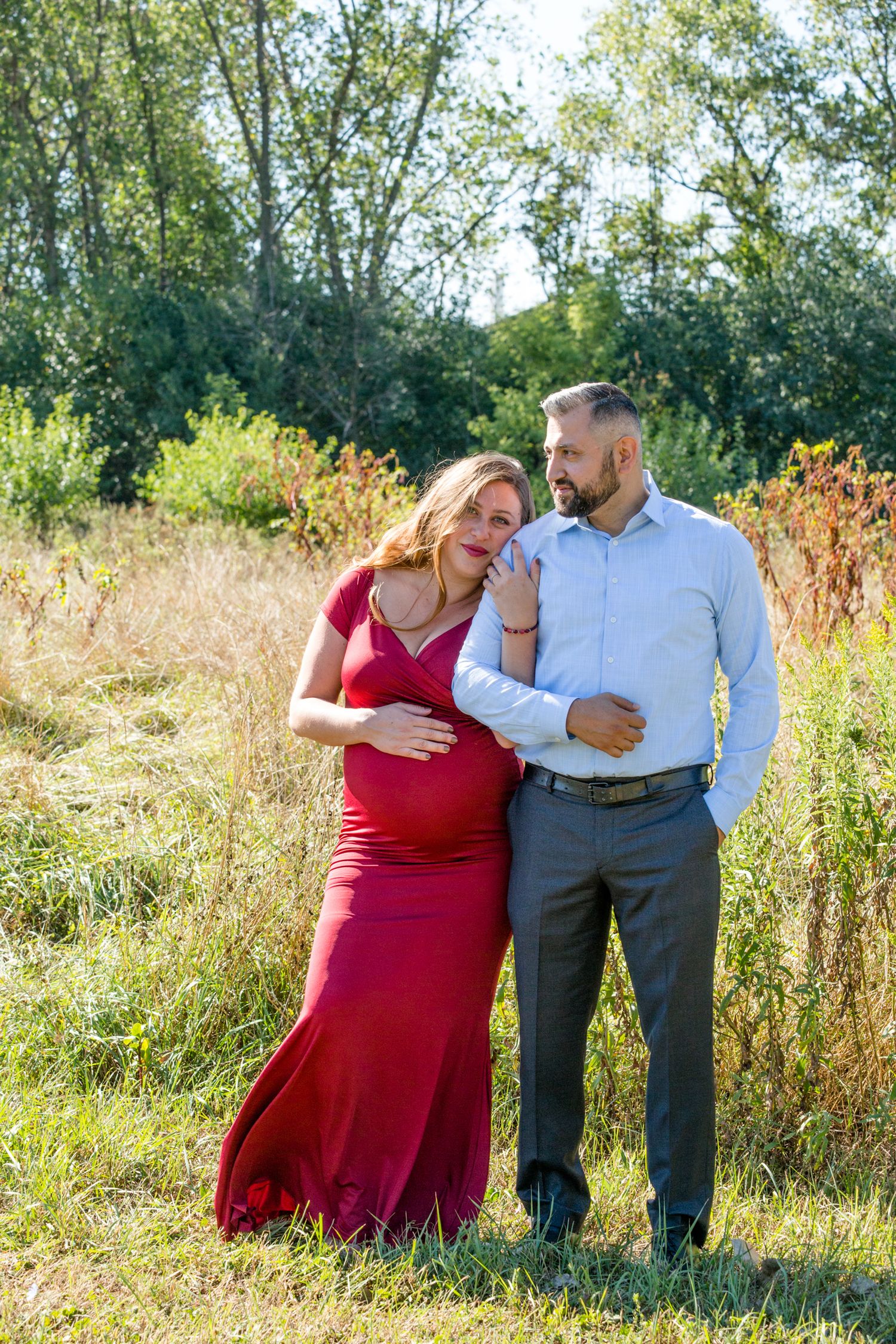 A couple shares an intimate moment during their maternity photoshoot in a golden field.