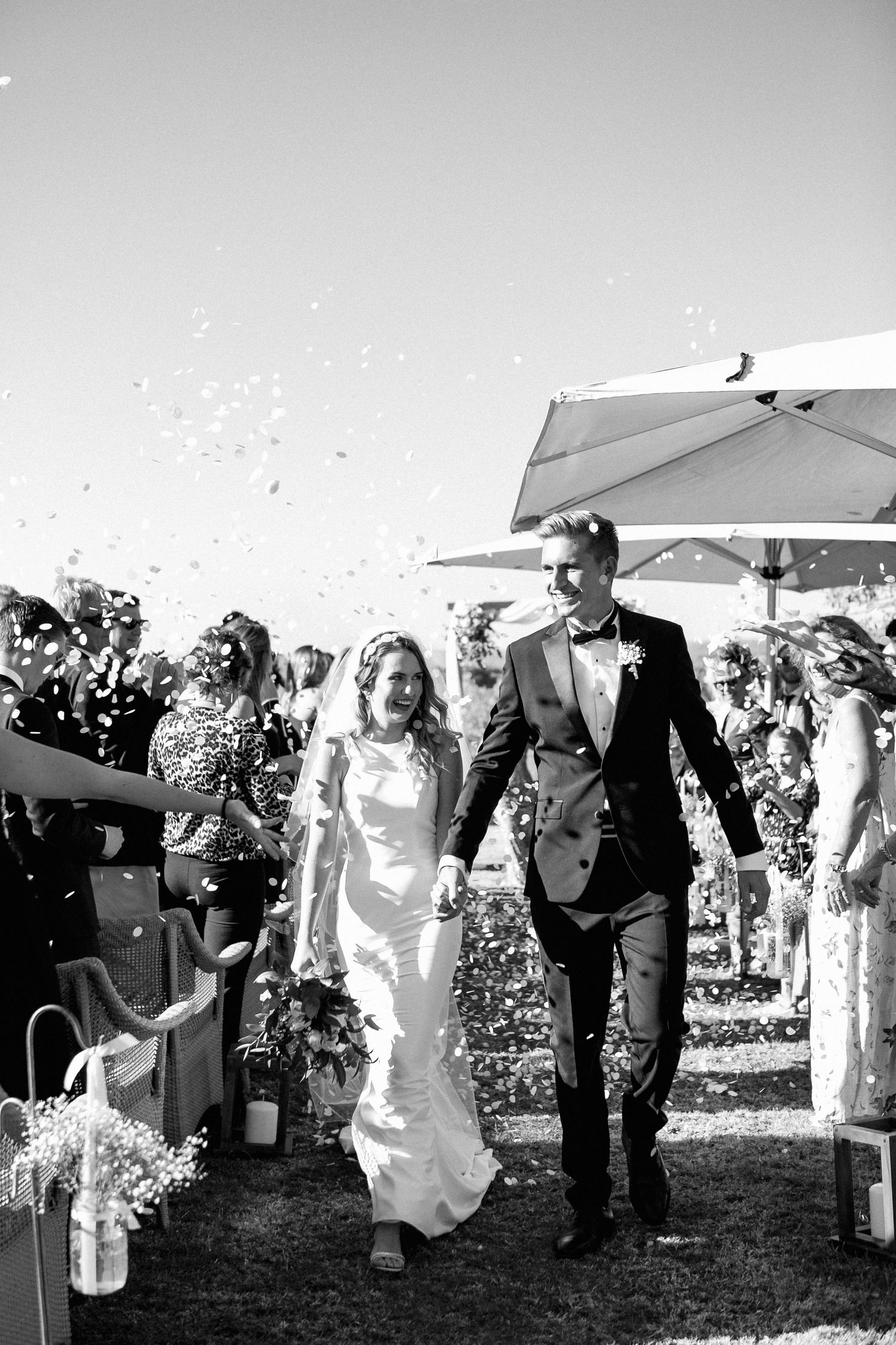James & Holly exciting their wedding ceremony at the Victoria  Falls Hotel while their guests shower them with confetti.