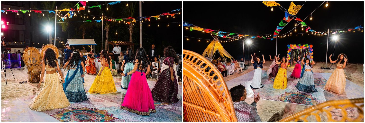 Colorful wedding reception on the beach with guests in vibrant attire dancing under string lights.