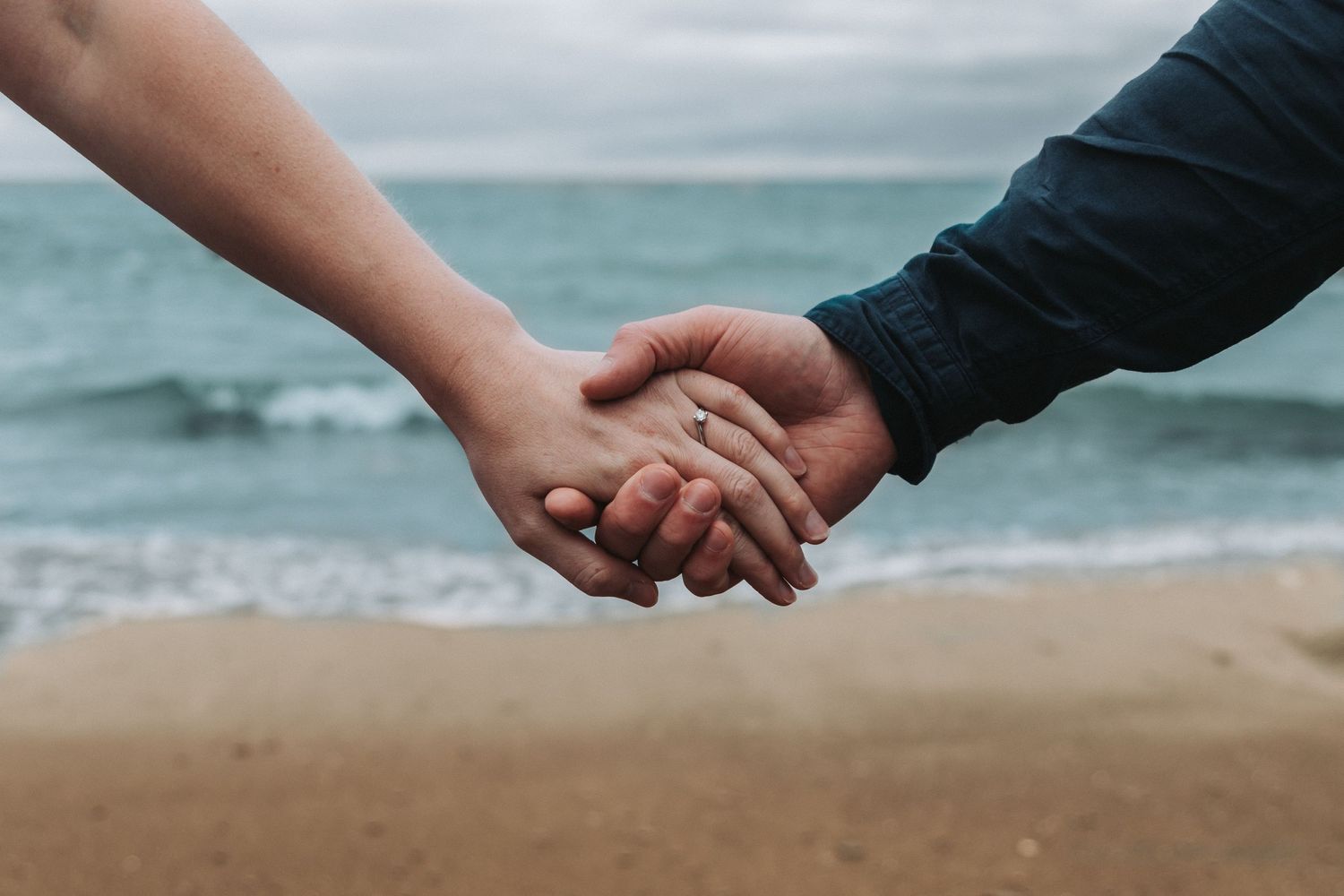 Couple on engagement shoot on a beach showing off engagement ring