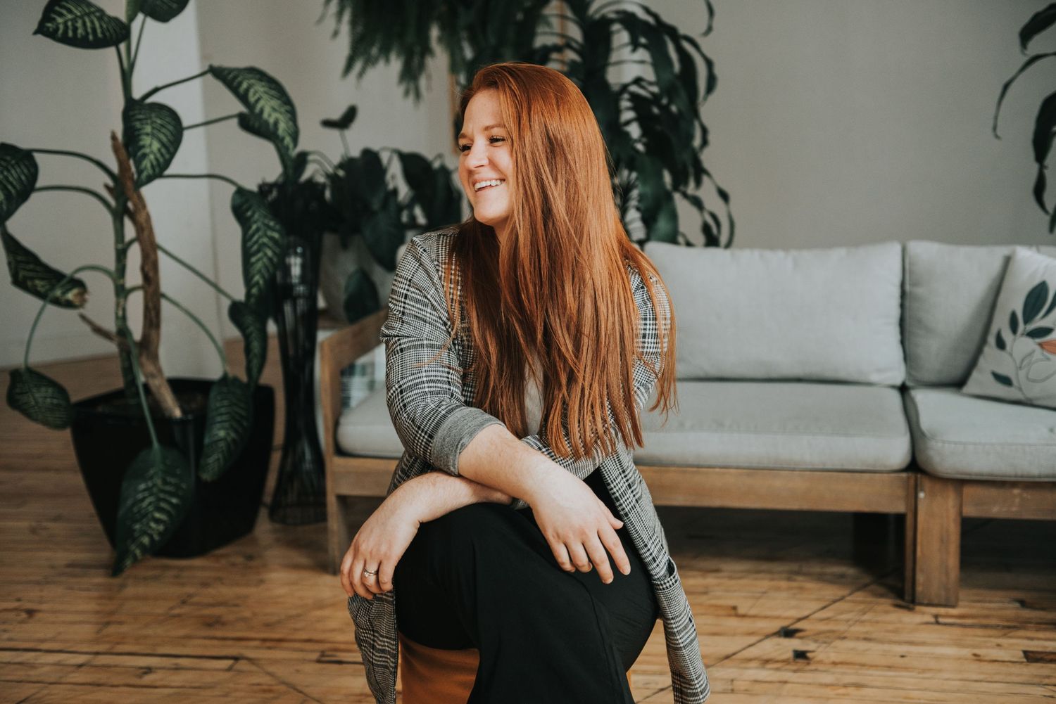 Relaxed indoor portrait with houseplants and modern furniture in warm tones.