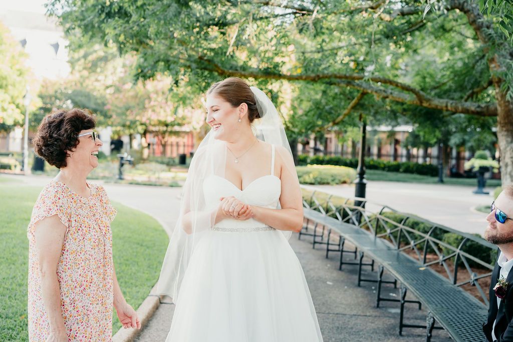 A bride and her mother share a laugh as they prepare to begin the ceremony inside of Jackson Square, New Orleans.