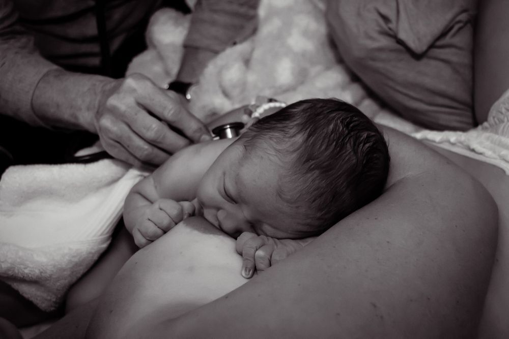 Intimate black and white photo of a newborn baby during first moments after birth.