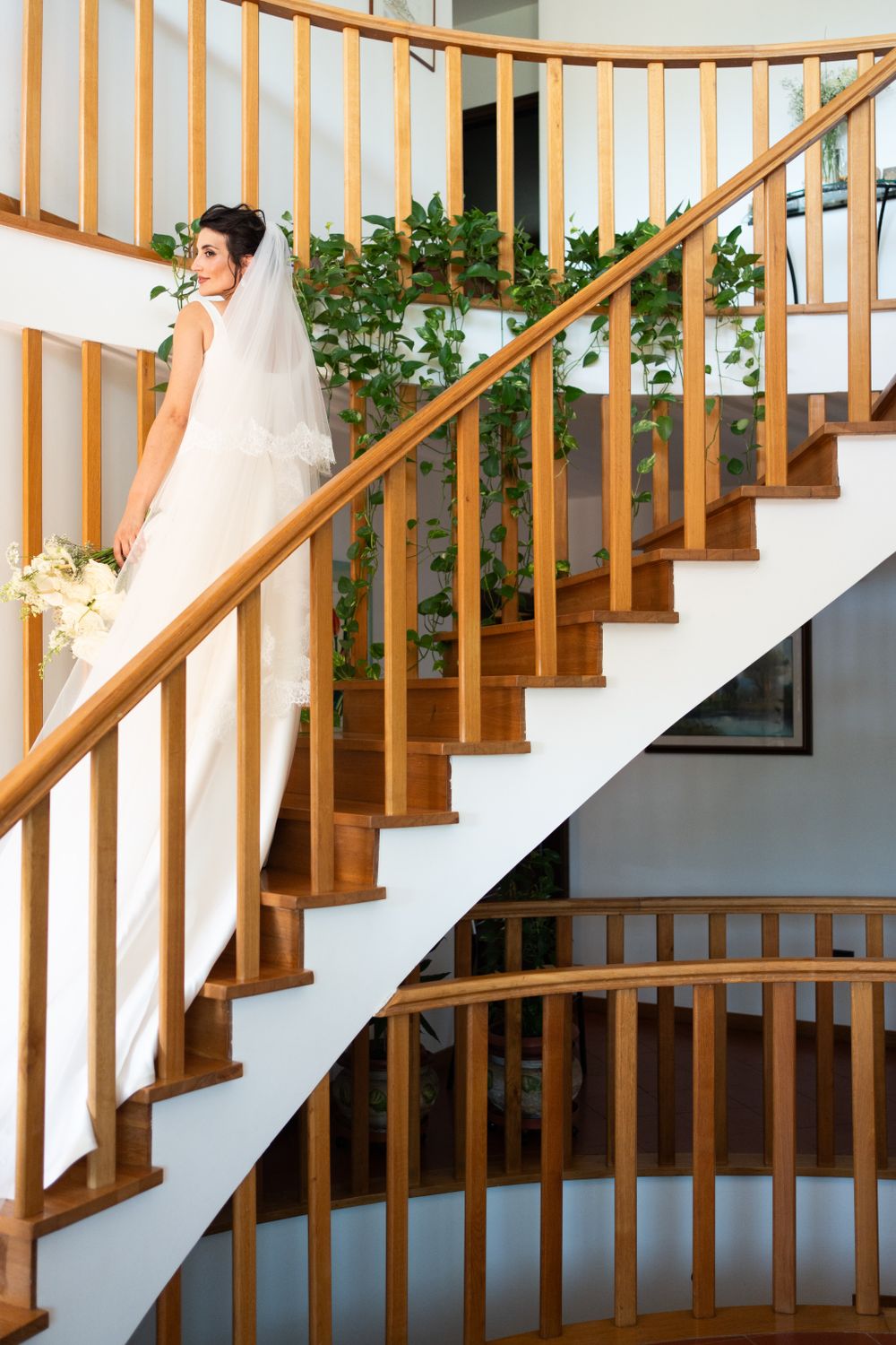 Elegant wooden staircase with white spindles and green floral decorations.
