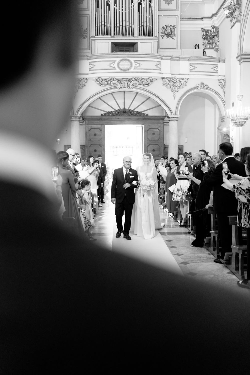 Black and white photo of a wedding ceremony procession in a grand cathedral.
