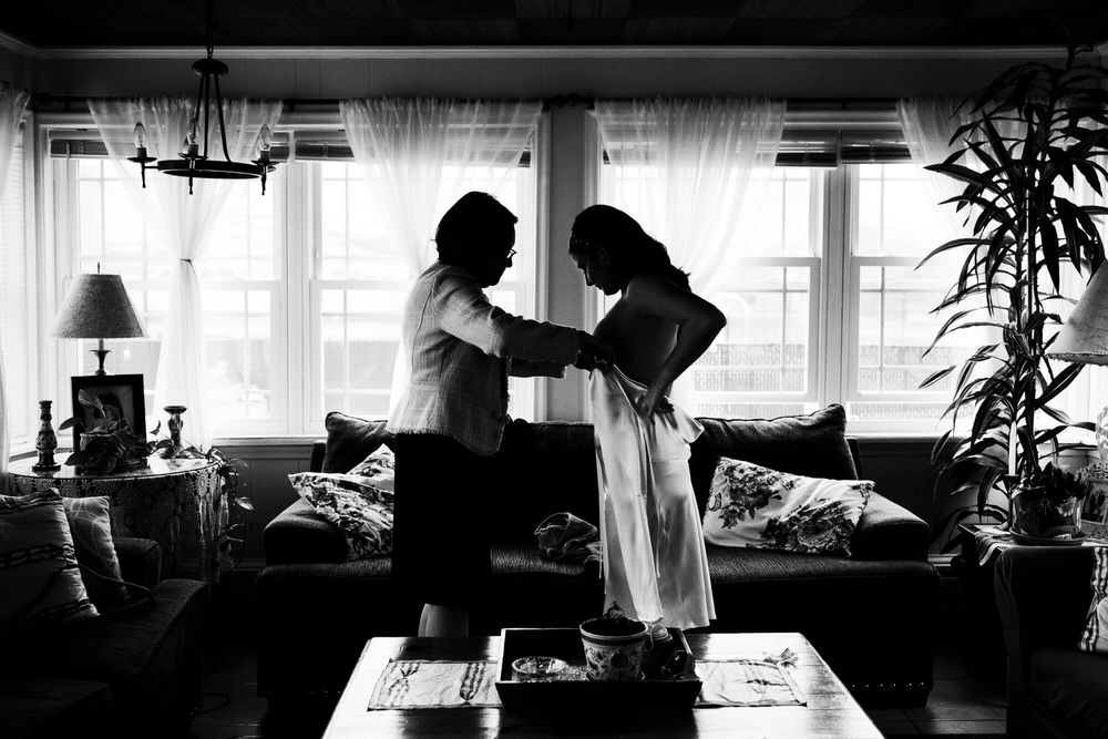 The groom's mother helps the bride into her wedding dress on the morning of their City Hall NYC wedding.