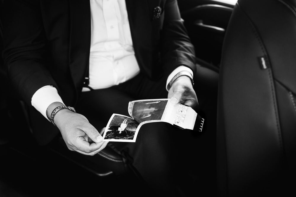 The groom peels apart an instant Polaroid photograph showing his bride on the lawn of their Long Island home.