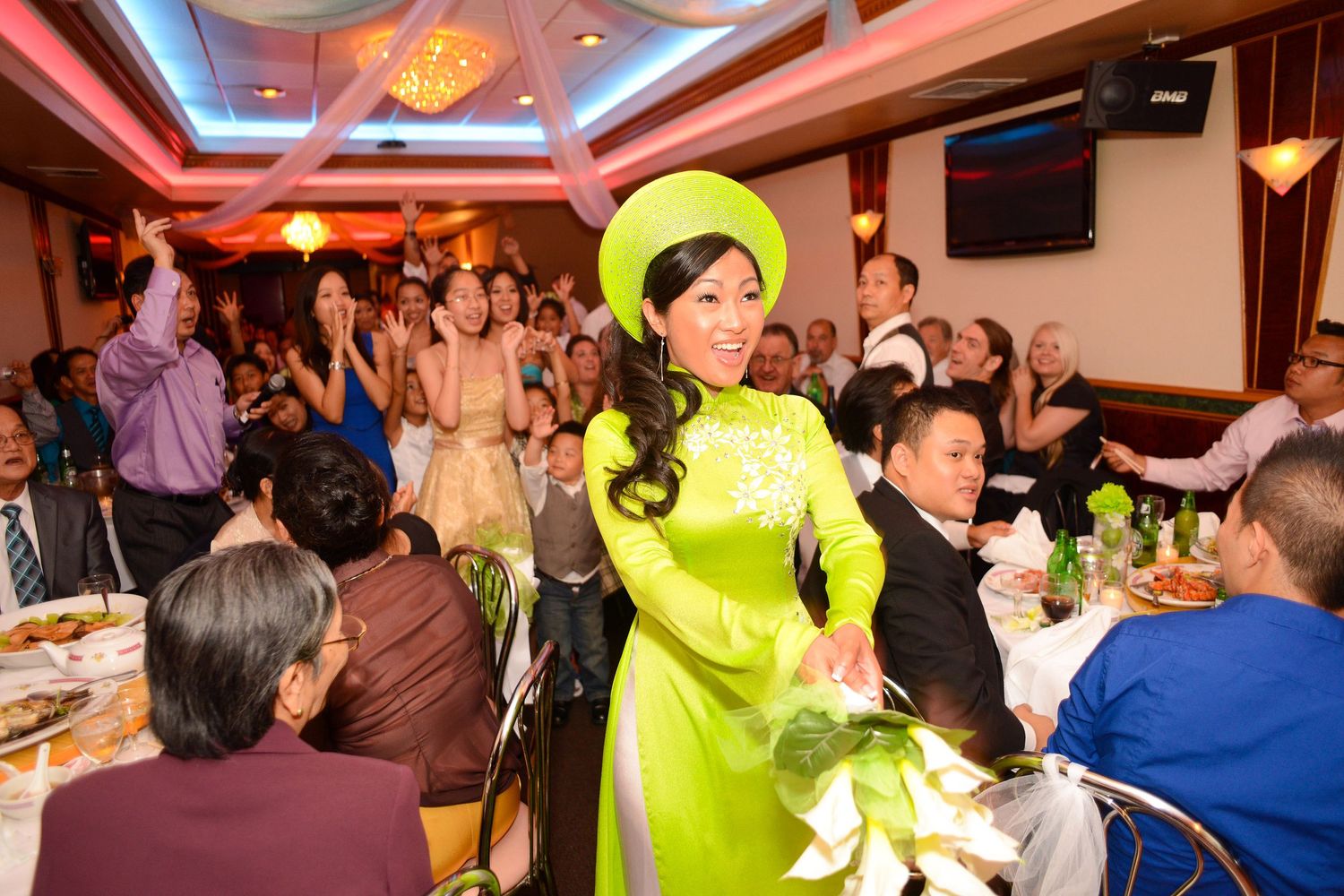 Guest in bright yellow traditional dress dancing at wedding reception.