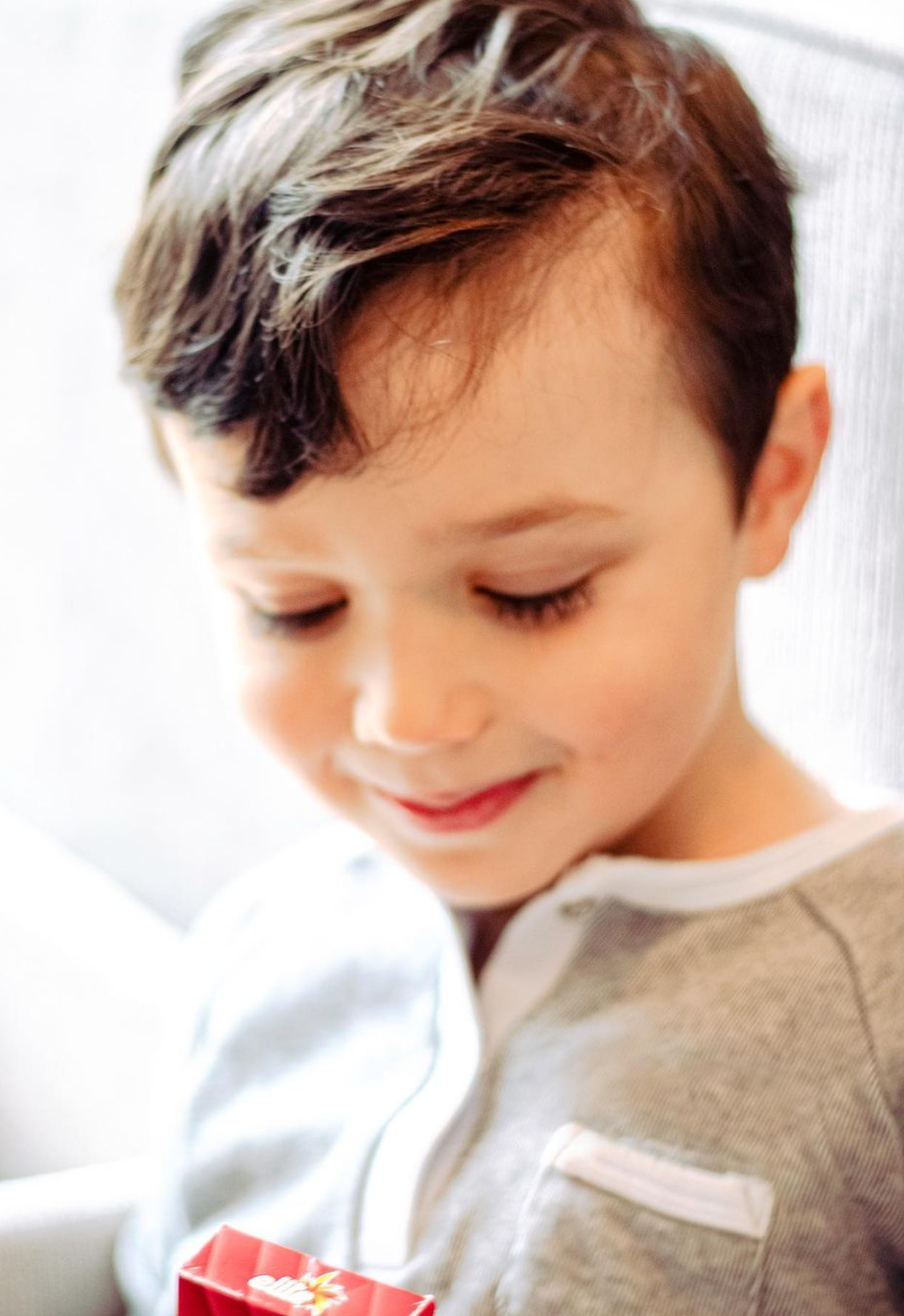 Boy smiling holding a box of gum. This is a lifestyle product photo, used for a company's ads and marketing campaigns.