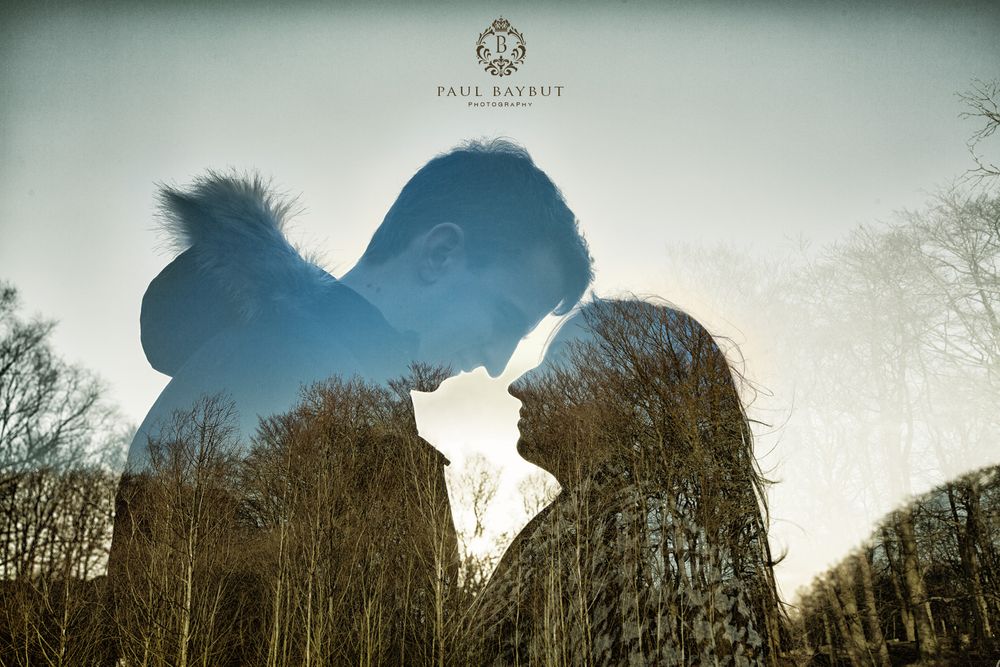 Double exposure image of newly engaged couple stood head to head in Worsley woods with trees and sky