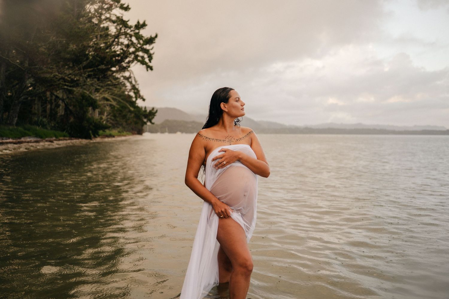 Ethereal beach photography session with flowing white dress against ocean backdrop at sunset.