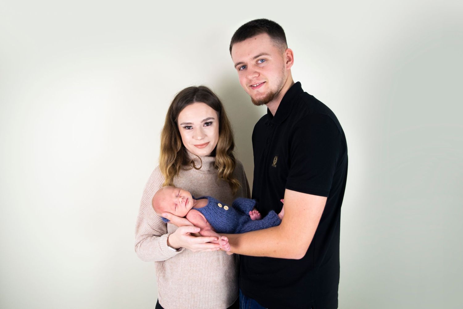 mum and dad holding baby boy during newborn session for family portraits taken by heather katie photography.