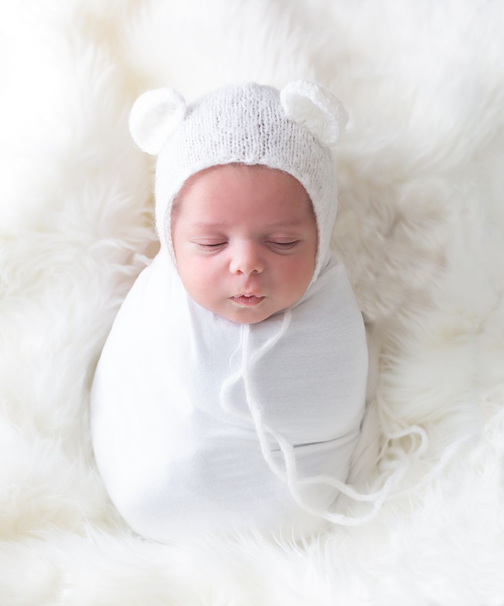 Series of artistic newborn portraits with baby wearing white against soft white backdrop.