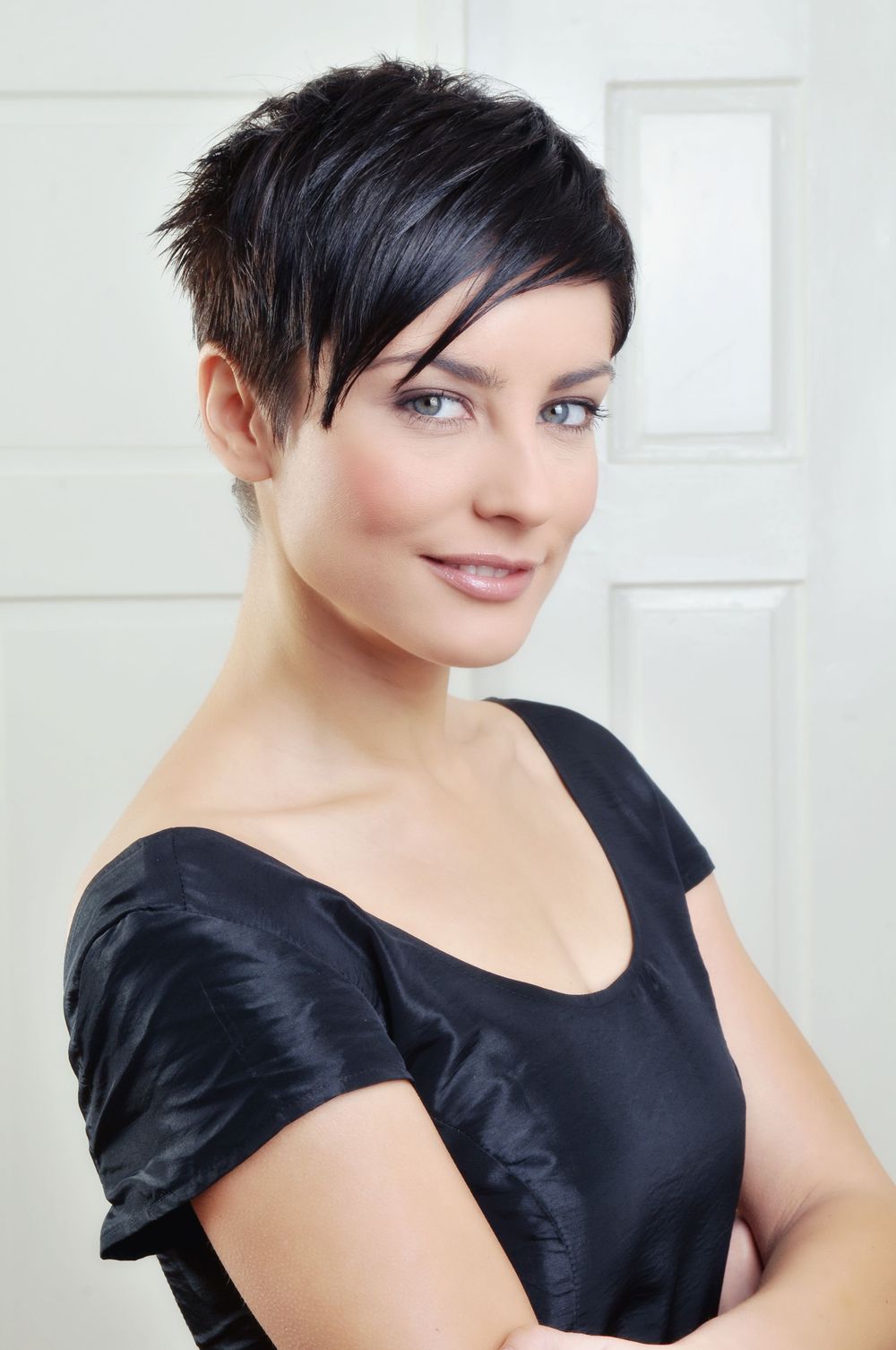 Modern studio portrait featuring short dark hair and black top against white background.