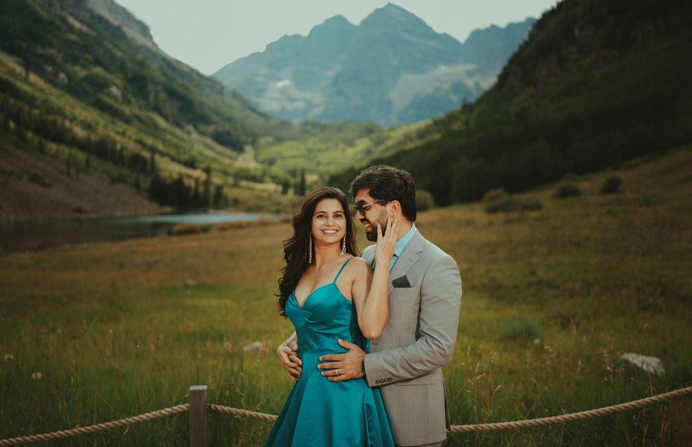 Couple in formal wear poses against stunning mountain landscape backdrop.