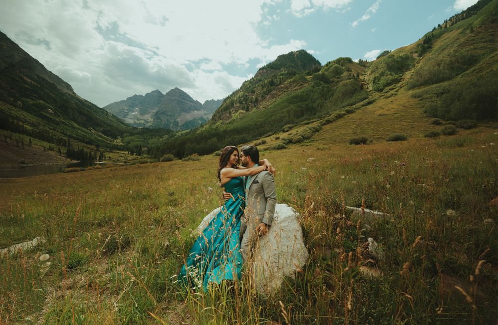 Romantic mountain engagement photo with couple in turquoise gown and grey suit.