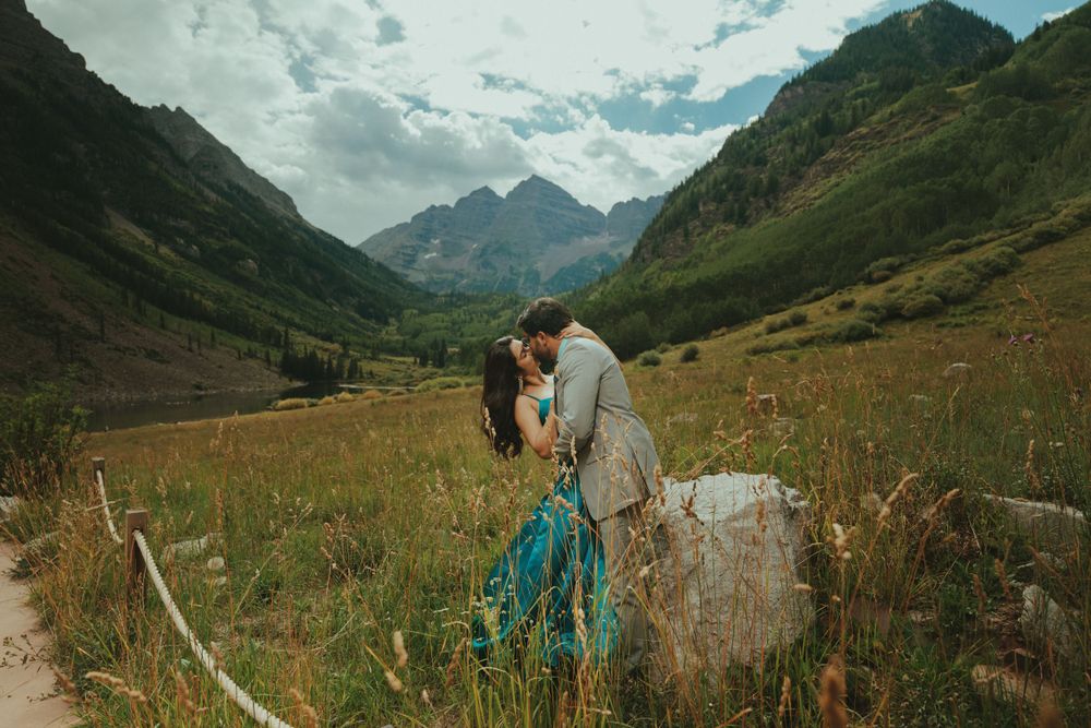 A romantic photoshoot in a stunning mountain valley with dramatic peaks and flowing dress against natural scenery.