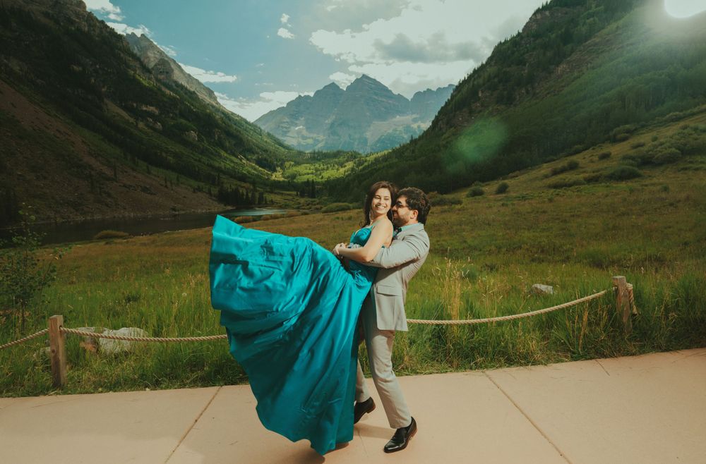 A twirling turquoise gown creates movement against a dramatic mountain backdrop on a sunny day.