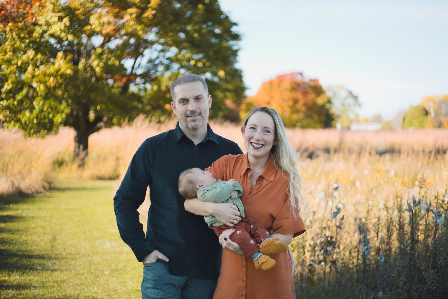 parents posing for camera holding 3 month old baby fall family photo