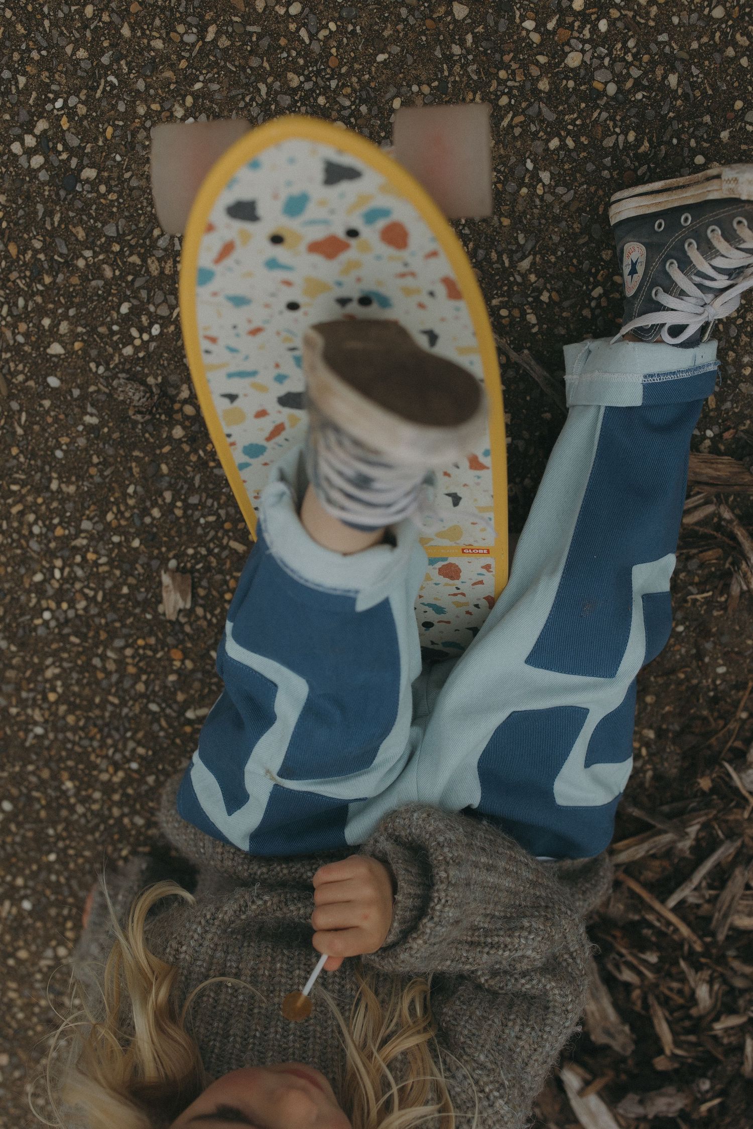 Close up of blue patterned leggings and gray knit sweater against asphalt background.