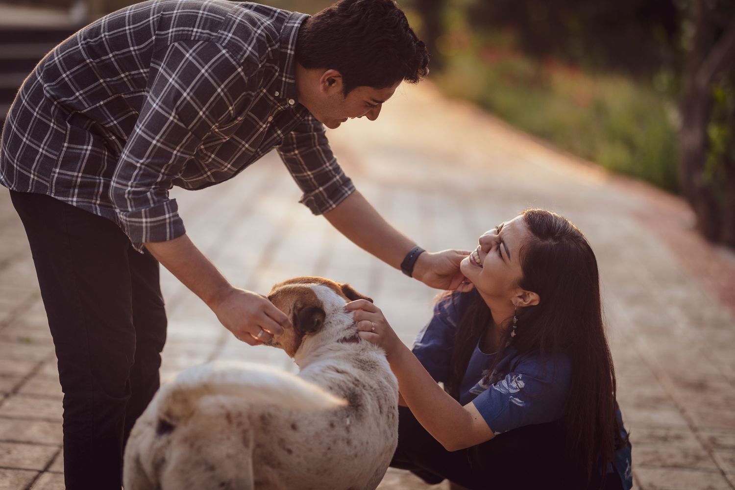 Playful moment between couple and their dog on outdoor path.