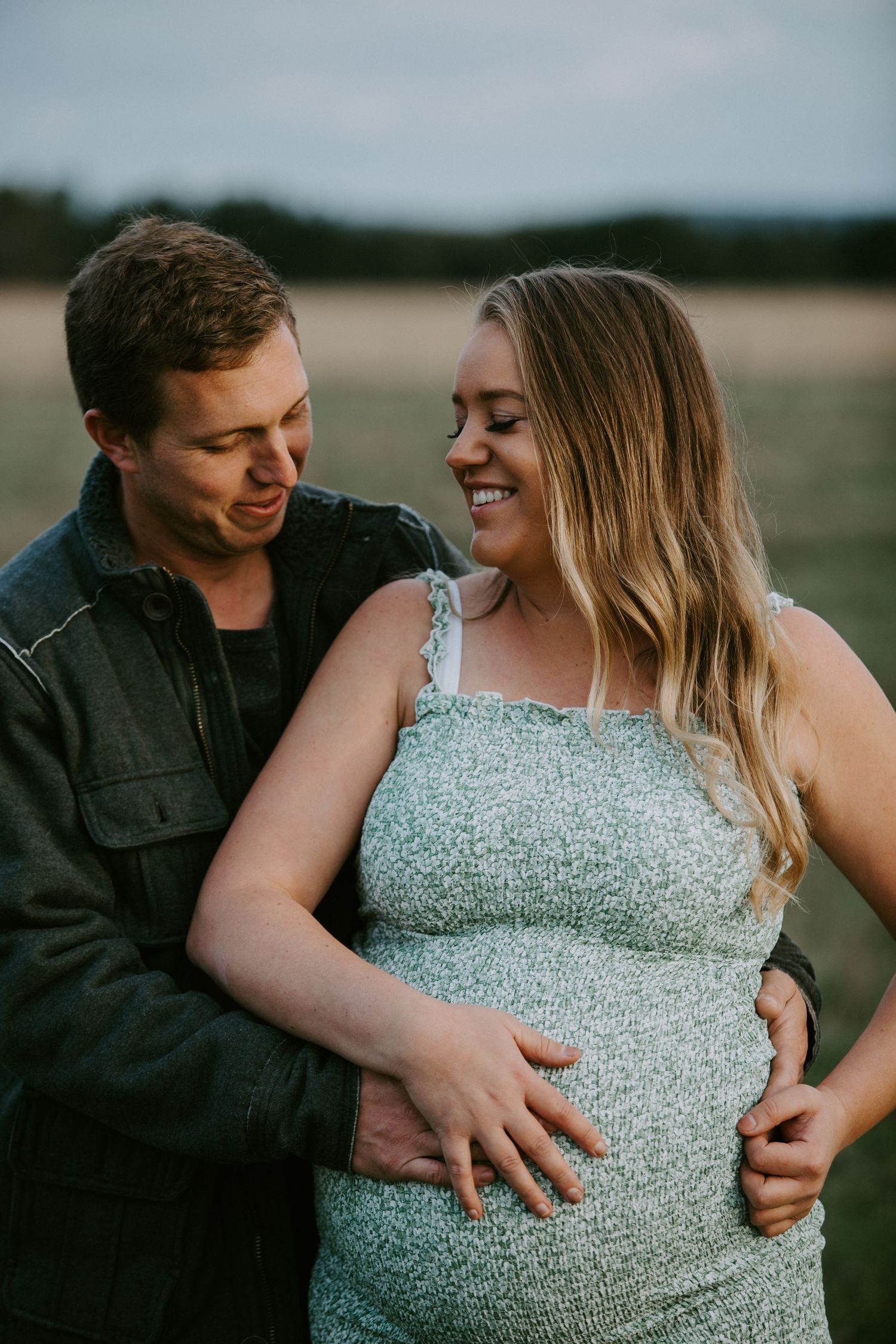 A couple shares intimate moments outdoors while showing off an engagement ring in a series of romantic photos.