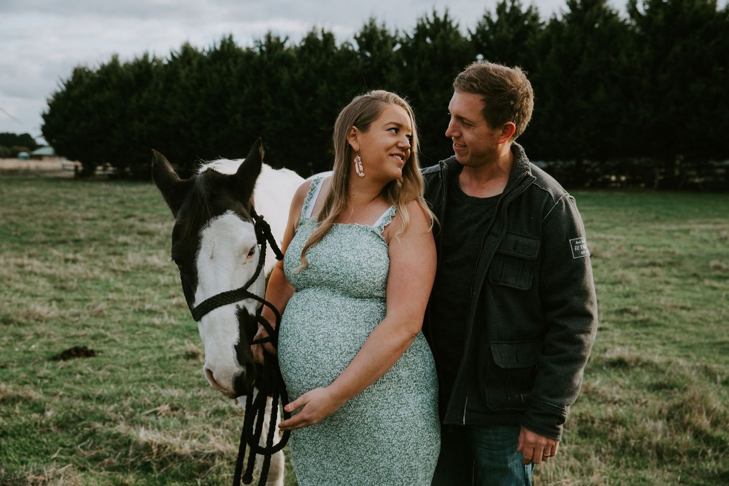 A couple in a field shares tender moments with their horse during a romantic countryside photoshoot.