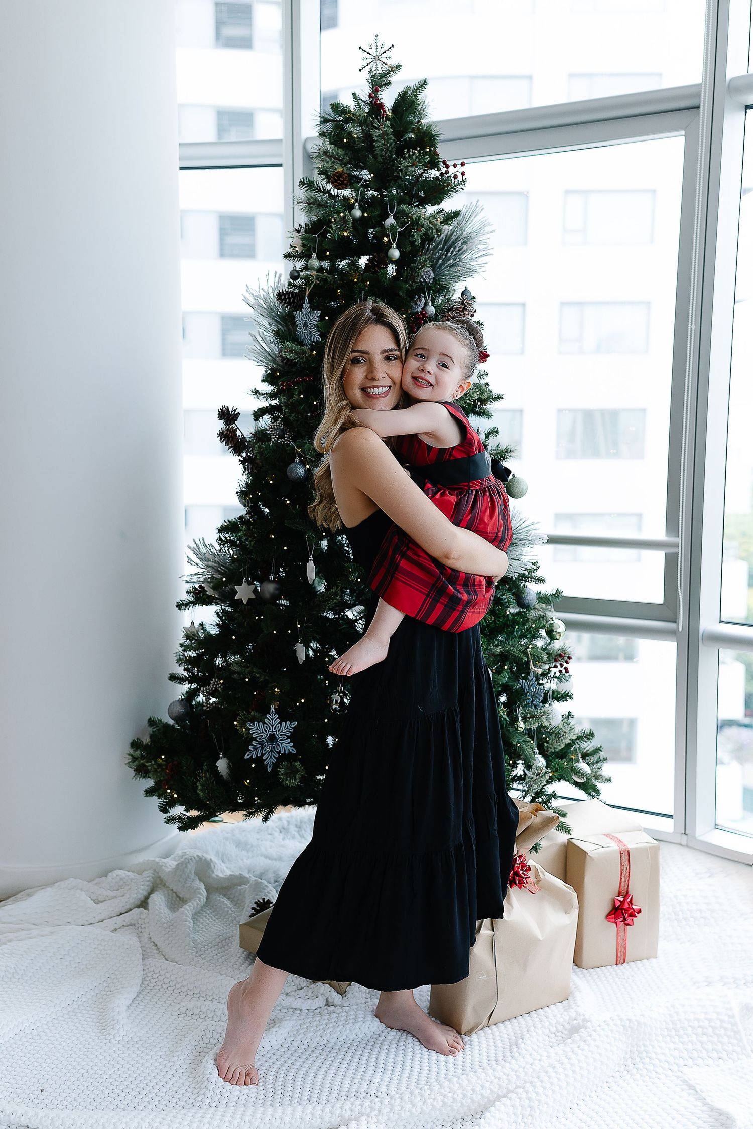 Festive holiday portrait in front of Christmas tree with matching red and black outfits.