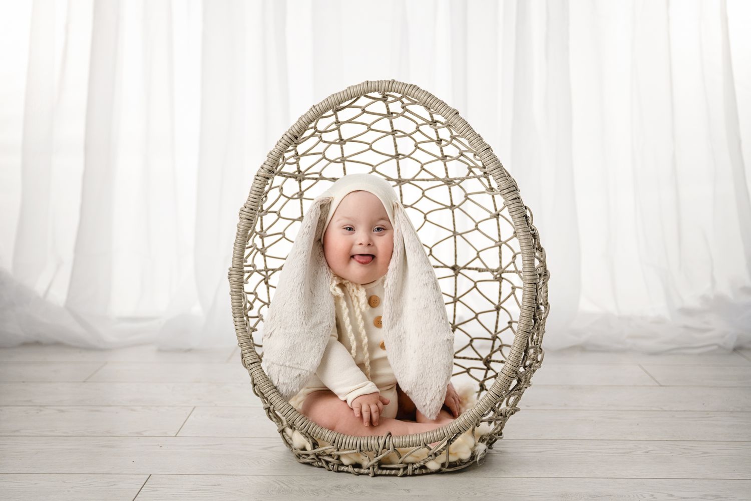 Suspended egg chair creates ethereal setting against white curtain backdrop.