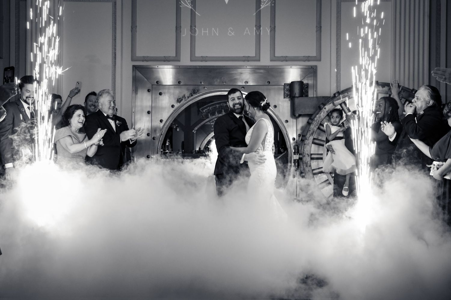 Couple shares first dance surrounded by fog and sparklers during wedding reception.