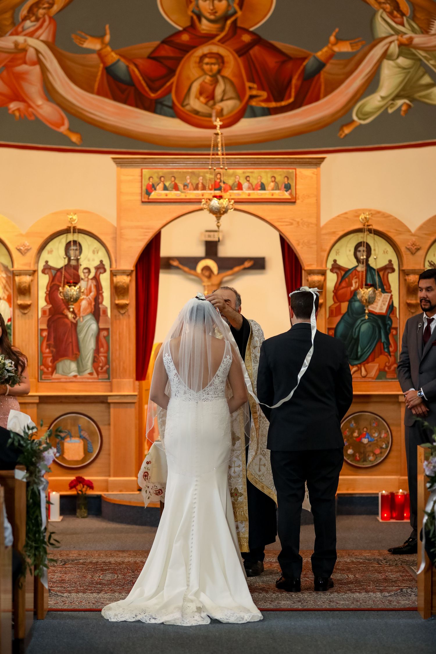 Interior of orthodox church with religious icons and couple standing at altar.