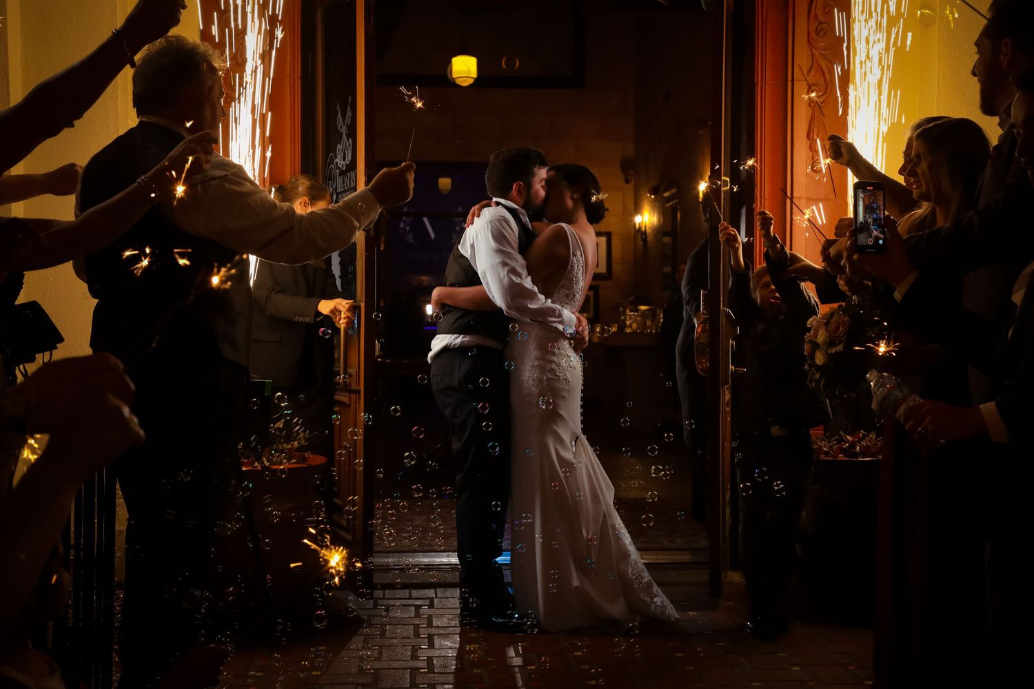 Couple shares romantic moment amid sparklers during evening wedding celebration.